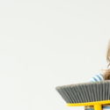 Child using a broom for spring cleaning, emphasizing indoor air quality maintenance and home cleanliness.