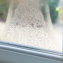 Glass window with condensation, revealing a blurred view of the outdoor landscape near Laney's Inc. home maintenance tips.