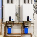 Tankless water heaters mounted on a wall with blue filtration systems, showcasing plumbing and HVAC solutions relevant to home maintenance.