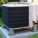 Modern air conditioning unit on a platform surrounded by grass, showcasing Laney's Inc. HVAC services for home maintenance.