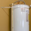 White water heater with pipes and gauge against neutral wall, featuring operational safety information for home maintenance.