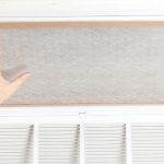 Hand reaching to replace a dirty air filter in an HVAC system, emphasizing the importance of timely filter changes for efficient airflow and indoor air quality.